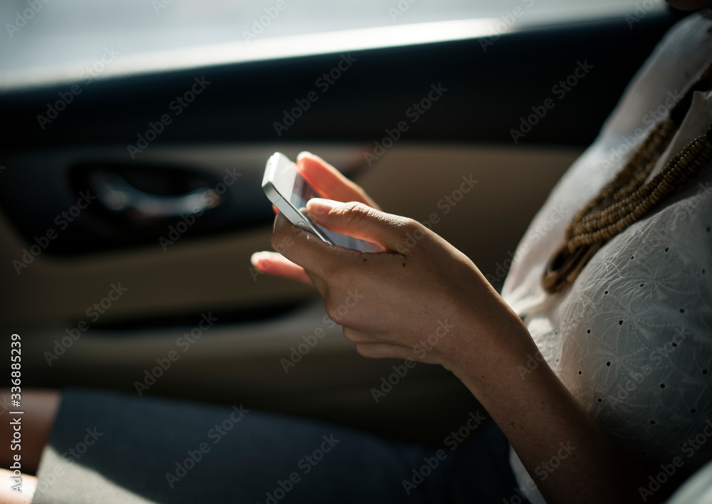 Businesswoman using mobile phone at back seat of the car