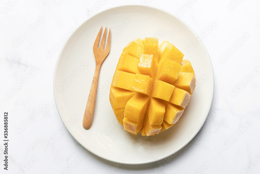 Mango slice with cubes on dish; ready to eat with wooden fork. Tropical fruits. Mango slice with cubes on dish; ready to eat with wooden fork. Tropical fruits.