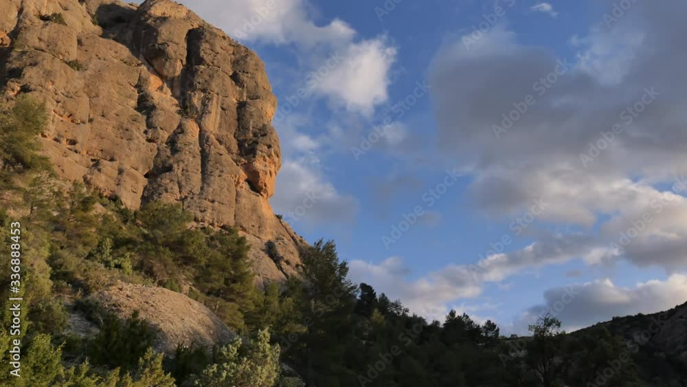 Ravine in Spain, during sunset, with moving clouds and a mountain cliff face coming into view. Ravine in Spain, during sunset, with moving clouds and a mountain cliff face coming into view.