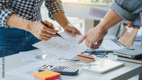 engineer Hand Drawing Plan On Blue Print with architect equipment discussing the floor plans over blueprint architectural plans at table in a modern office.