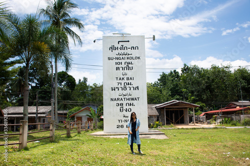 Travelers thai woman travel visit for take photo with Landmarks big milestone on the road information distance at rural on August 16, 2019 in Narathiwat, Thailand photo