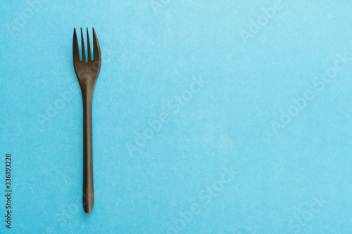 black plastic fork and knife on a blue background, top view, selective focus