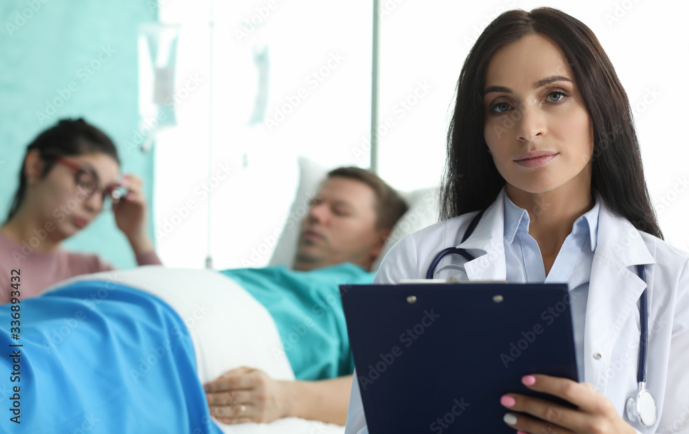 Doctor with folder is standing in palette sick man. Patient are monitored by staff on duty. Remote monitoring all vital functions patient. Observation medical personnel resuscitation service Doctor with folder is standing in palette sick man. Patient are monitored by staff on duty. Remote monitoring all vital functions patient. Observation medical personnel resuscitation service