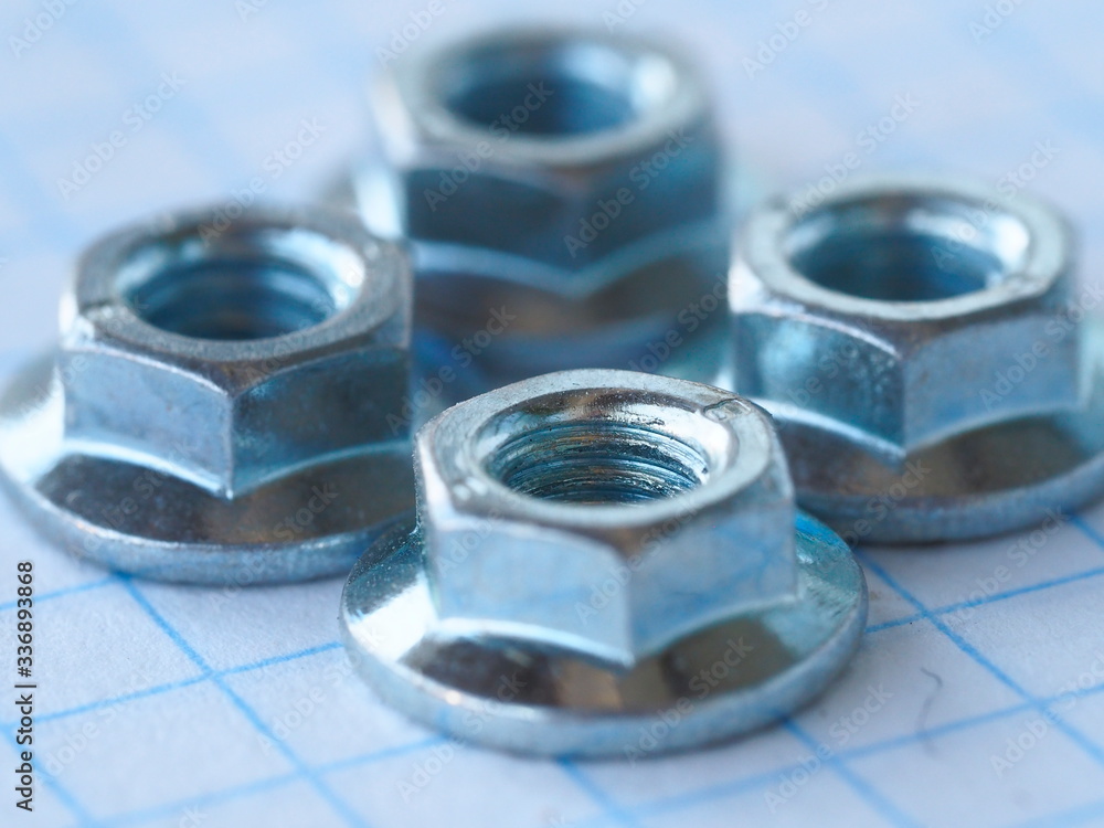 nuts made of stainless steel, close-up, on a sheet of paper to cel nuts made of stainless steel, close-up, on a sheet of paper to cel