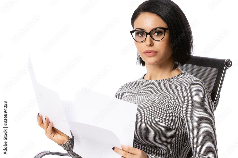 Pensive young business woman in glasses sitting on chair with paper documents. Isolated over white background. Achievement business career concept. Pensive young business woman in glasses sitting on chair with paper documents. Isolated over white background. Achievement business career concept.