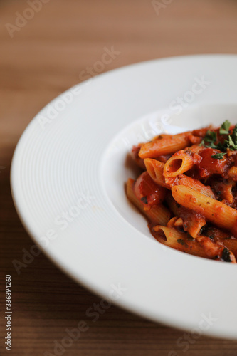 Penne arrabiata pasta tomato sauce with spices italian food on wood background