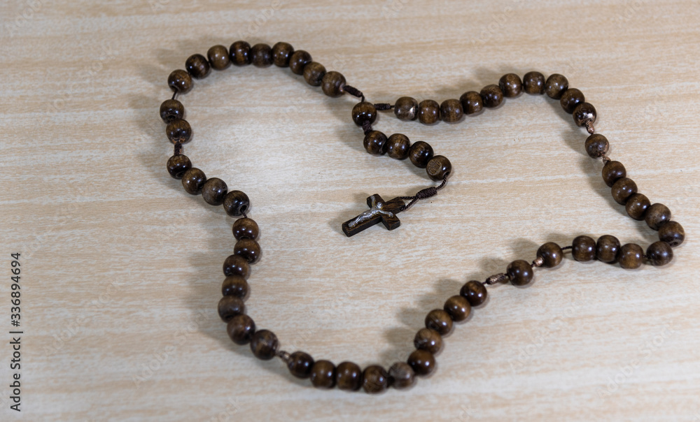 Rosary and crucifix symbols of Catholicism on light wooden background Rosary and crucifix symbols of Catholicism on light wooden background