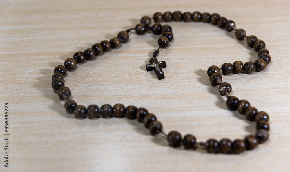 Rosary and crucifix symbols of Catholicism on light wooden background Rosary and crucifix symbols of Catholicism on light wooden background