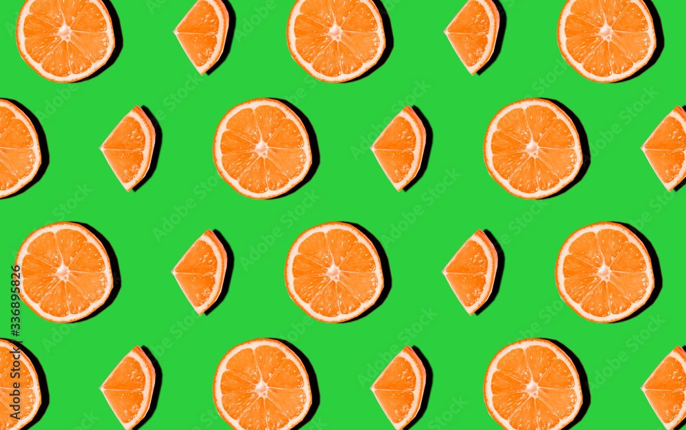 Trend pattern of oranges on a green background. Flat lay. Minimalistic concept, hard light, shadows. Trend pattern of oranges on a green background. Flat lay. Minimalistic concept, hard light, shadows.