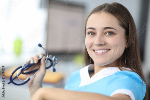 Close-up of cheerful therapist looking at camera with happiness and smile. Beautiful practitioner holding stethoscope. Healthcare and medicine concept