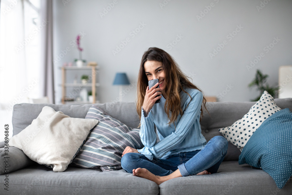 Smiling woman with smartphone at home on the couch. Online shoping. Smiling woman with smartphone at home on the couch. Online shoping.