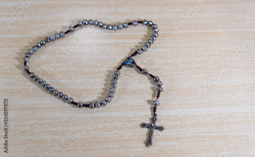 Rosary and crucifix symbols of Catholicism on light wooden background