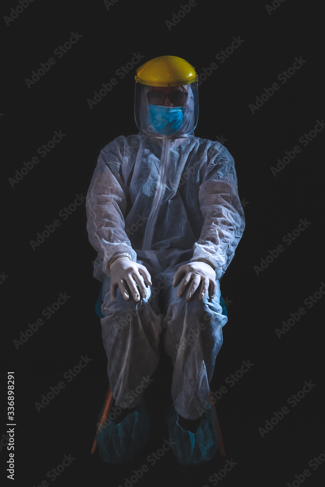 Medical doctor, nurse, surgeon, psychologist working with protective mask, glasses and gloves helping people in the days of panic, pandemic - studio shot on black background.