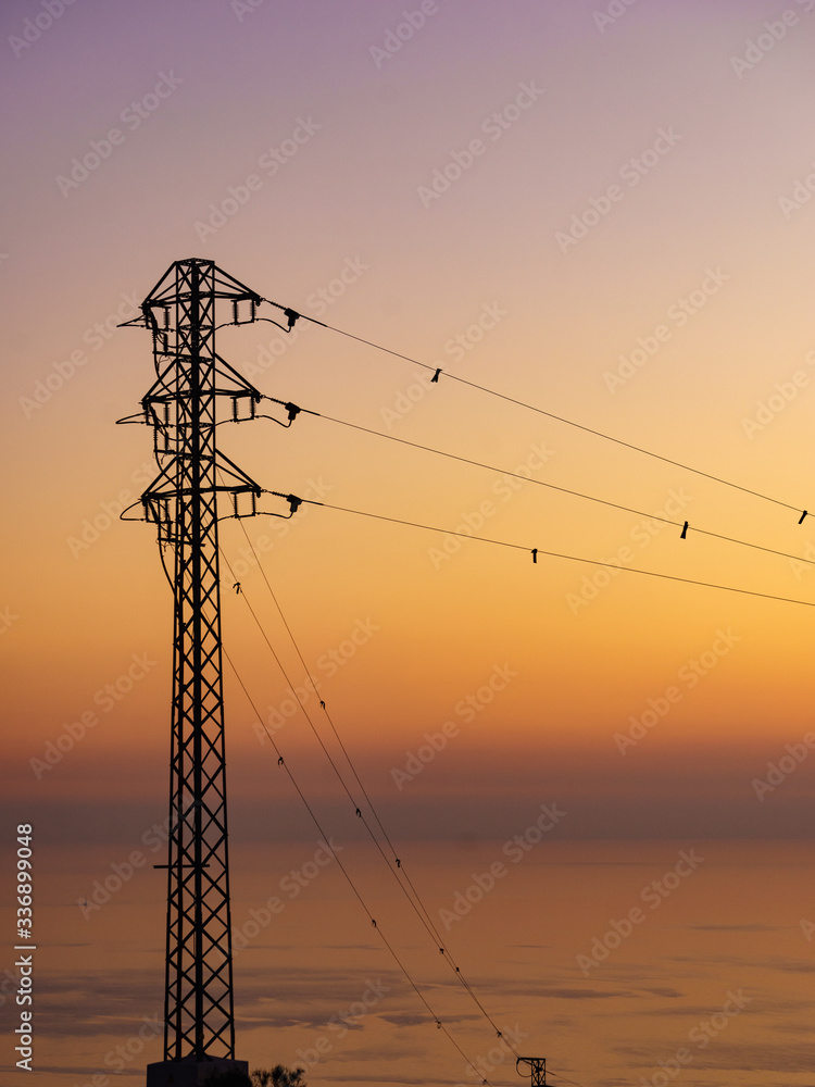 High voltage towers on coast at sunset