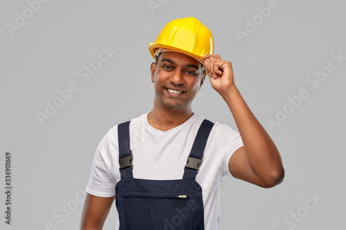 profession, construction and building - happy smiling indian worker or builder in helmet over grey background