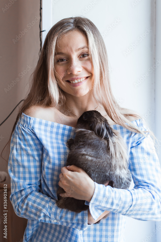 Pet and Easter concept - Attractive girl hugging brown rabbit at home.