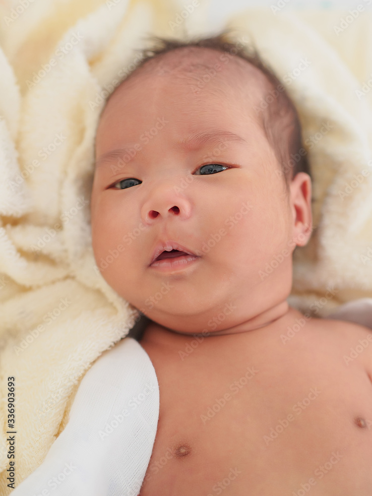 The Asian baby girl just took a shower. She is lying down on the soft and clean towel and looking at her mother. The Asian baby girl just took a shower. She is lying down on the soft and clean towel and looking at her mother.