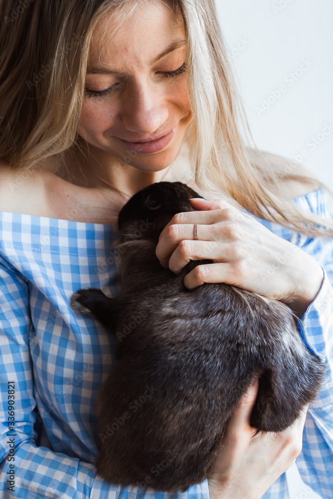 Pet and Easter concept - Attractive girl hugging brown rabbit at home, close-up.