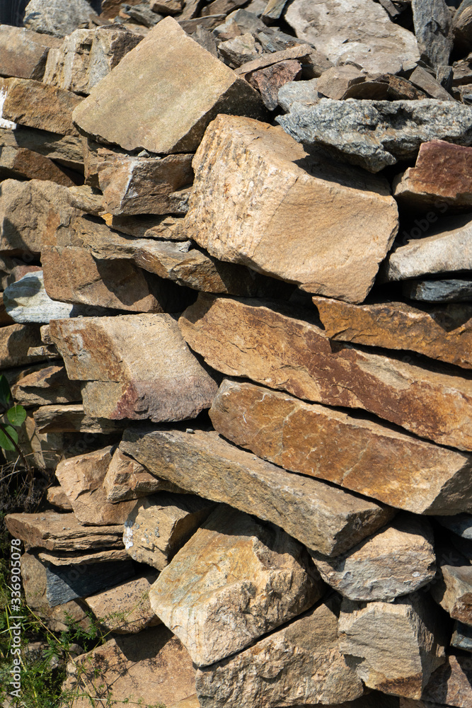 Stone natural flagstone piled in a pile. Natural stone flagstone, laid in uneven rows. Background of the flagstone Stone natural flagstone piled in a pile. Natural stone flagstone, laid in uneven rows. Background of the flagstone