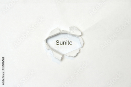 Word sunite on white isolated background, the inscription through the wound hole in the paper. Stock photo for web and print with empty space for text and design. photo