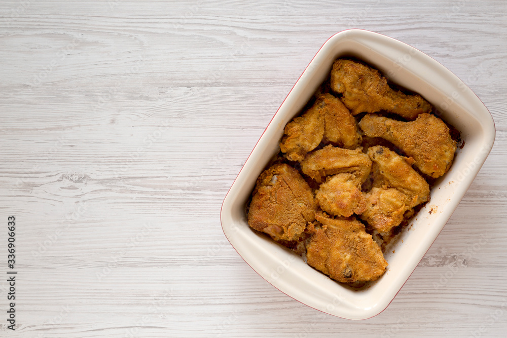 Crispy homemade oven baked fried chicken in a dish on a white wooden surface, top view. Flat lay, overhead, from above. Space for text. Crispy homemade oven baked fried chicken in a dish on a white wooden surface, top view. Flat lay, overhead, from above. Space for text.