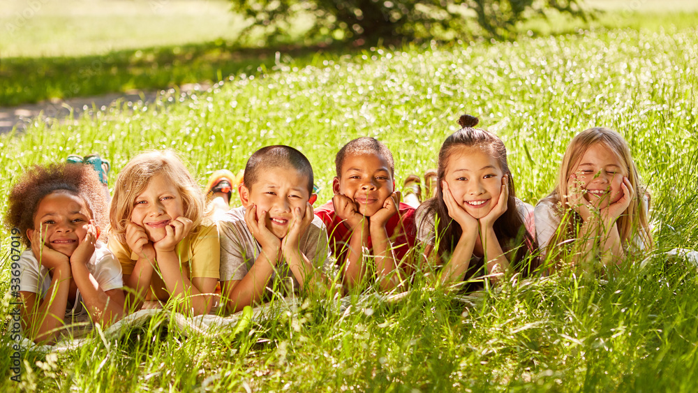 Glückliche multikulturelle Kinder im Sommer auf Wiese Glückliche multikulturelle Kinder im Sommer auf Wiese