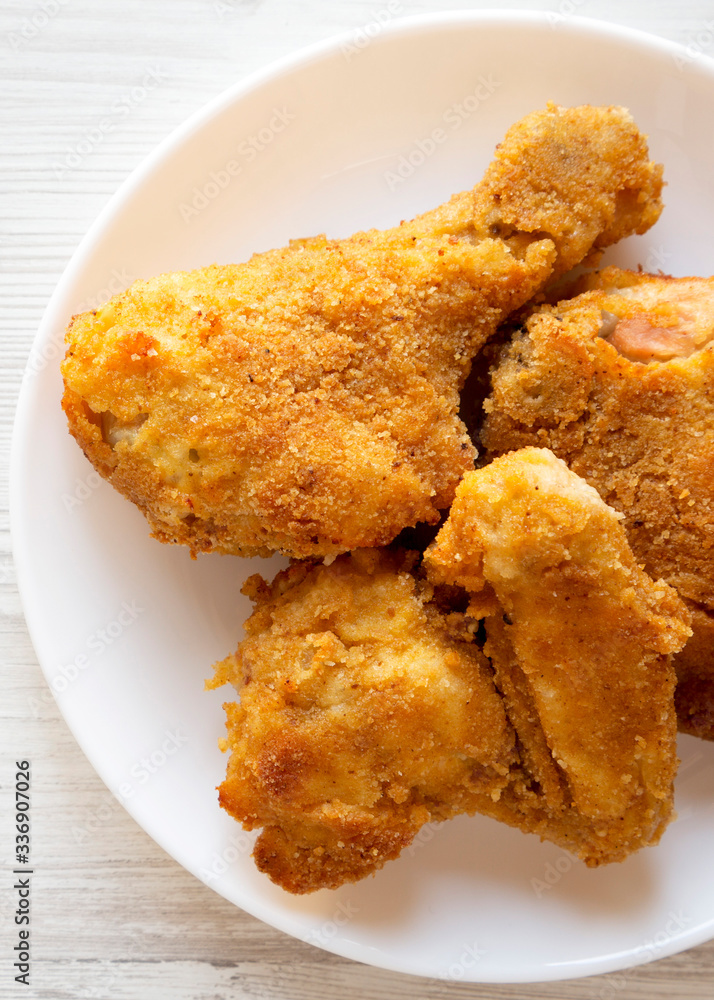 Homemade tasty oven baked fried chicken on a white plate on a white wooden table, top view. Overhead, from above, flat lay. Homemade tasty oven baked fried chicken on a white plate on a white wooden table, top view. Overhead, from above, flat lay.