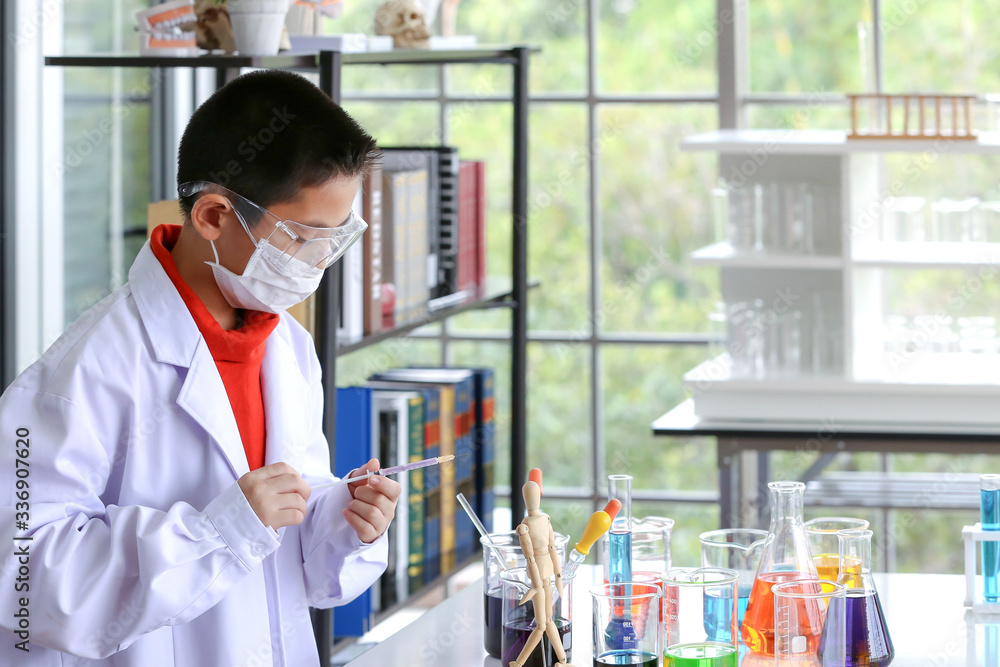 The young scientist is standing in front of his own experiment in the lab. Young kids in science lab study samples. Test for virus detection. The young scientist is standing in front of his own experiment in the lab. Young kids in science lab study samples. Test for virus detection.
