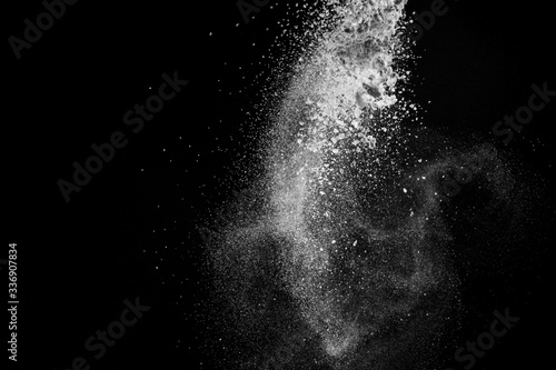 Burst of white powder with flour and sugar creating a beautiful pattern isolated on black background