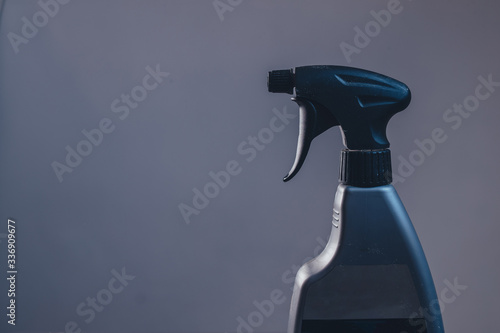 Side view of a plastic spray bottle for cleaning and operating it. Drops from bottle are being sprayed all over the place. Side view of an operational plastic spray bottle.