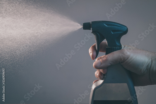Canvas Print Bare hand holding a spray bottle for cleaning and operating it