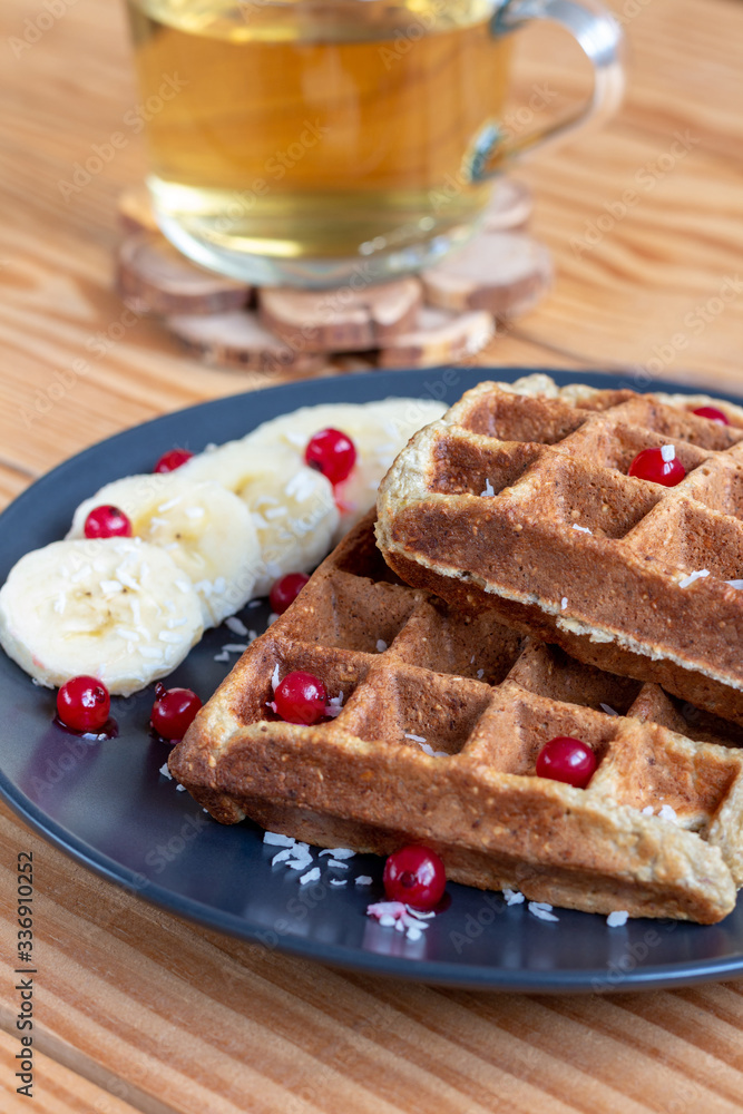 Belgian waffles with red berries and bananas on a wooden background Belgian waffles with red berries and bananas on a wooden background