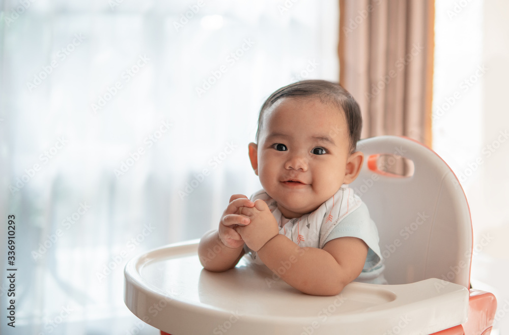 happy asian baby feeding time sitting on highchair happy asian baby feeding time sitting on highchair
