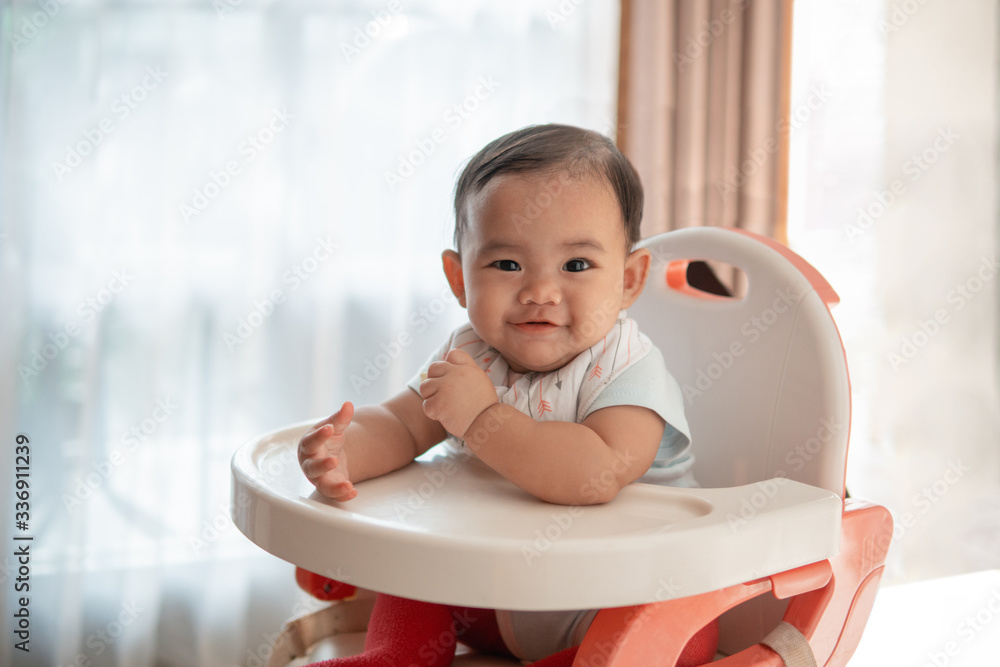 happy asian baby feeding time sitting on highchair