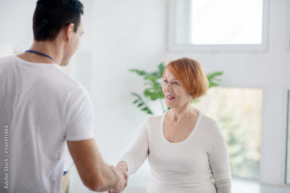 Obraz premium Positive nice elderly woman greeting her coach