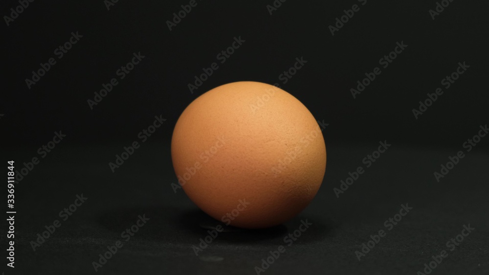 Brown egg rotating on black background. Close up. Brown egg rotating on black background. Close up.