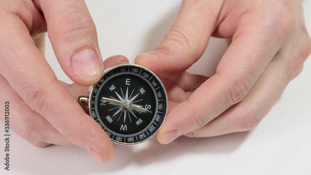 Hand holding a compass on white background. Close up. Hand holding a compass on white background. Close up.