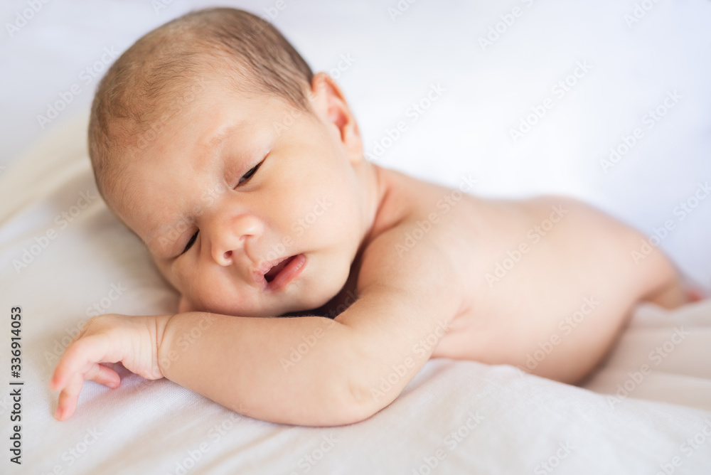 Newborn baby boy lying and sleeping on white bed at home Newborn baby boy lying and sleeping on white bed at home