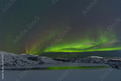 Aurora and stars in the sky .The rocks and ground are covered with snow.Arctic.