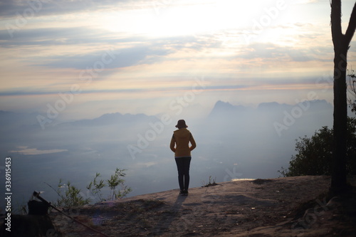 Woman standing on a cliff waiting for sunrise in Phu Kradueng National Park, Loei, Thailand
