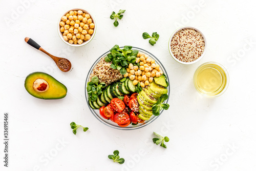 Veggie bowl. Vegetable salad with quinoa, avocado, tomato, spinach and chickpeas - on white table. Top view