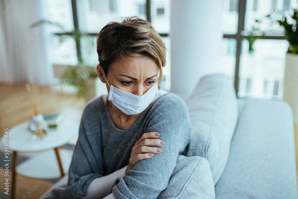Sad woman wearing face mask and thinking while sitting at home during coronavirus lockdown. Sad woman wearing face mask and thinking while sitting at home during coronavirus lockdown.