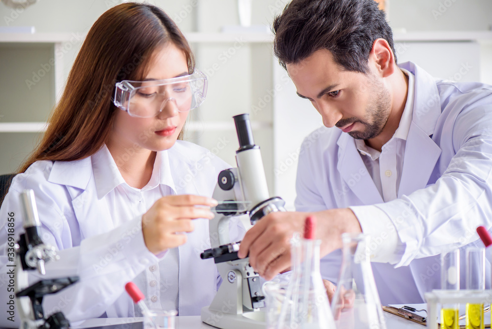 Attractive happiness scientist lab technician assistant analyzing sample in test tube at laboratory. Medical, pharmaceutical and scientific research and development concept. Attractive happiness scientist lab technician assistant analyzing sample in test tube at laboratory. Medical, pharmaceutical and scientific research and development concept.