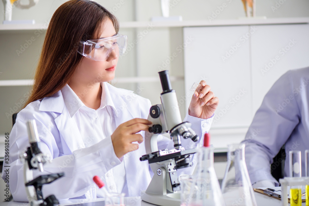 Attractive young Asian scientist woman lab technician assistant analyzing sample in test tube at laboratory. Medical, pharmaceutical and scientific research and development concept. Attractive young Asian scientist woman lab technician assistant analyzing sample in test tube at laboratory. Medical, pharmaceutical and scientific research and development concept.