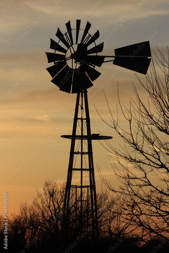 Kansas Windmill silhouette at Sunset with a tree out in the country north of Hutchinson Kansas USA. Kansas Windmill silhouette at Sunset with a tree out in the country north of Hutchinson Kansas USA.