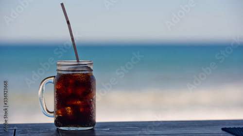 Cold refresh drink with ice on the table by the sea. Kitchen background.
