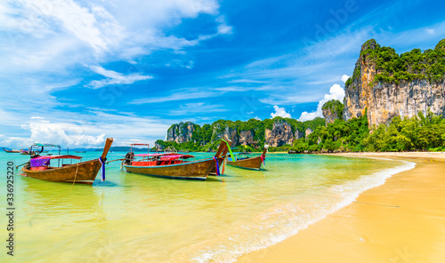 Beautiful view of long tail boats on water in Railay beach bay, Thailand, Krabi town. Famous tourist destination for vacation in tropical paradise. Beautiful summer day. Big limestone hill and rock © Martin