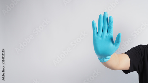 Stop hand sign with blue glove on white background.