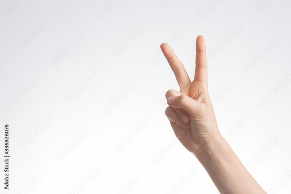Kid hand shows victory gesture, point number two on white wall background Kid hand shows victory gesture, point number two on white wall background