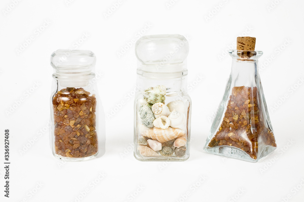 glass containers filled with natural fine ambers and shells on a white background glass containers filled with natural fine ambers and shells on a white background